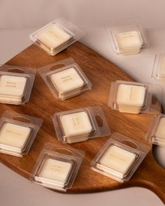 several square candles sitting on top of a wooden board with clear plastic holders around them