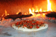 an uncooked pizza sitting in front of a fire