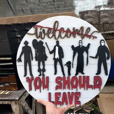 a hand holding up a sign that says, welcome you should leave with silhouettes on it