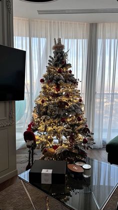 a christmas tree in the corner of a living room next to a window with curtains