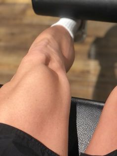 the legs of a person who is doing exercises on a stationary exercise bench with a bar