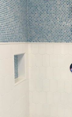 a bathroom with blue and white tiles on the walls, shower head and hand held faucet