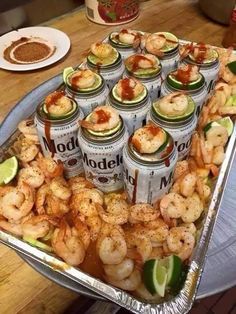 there are many cans of food on the table with shrimp in them and limes