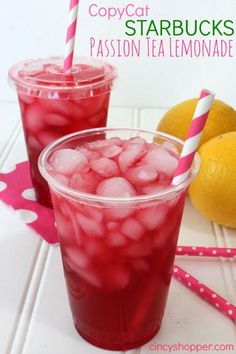 two glasses filled with red liquid next to lemons