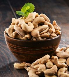 a bowl filled with cashews on top of a wooden table