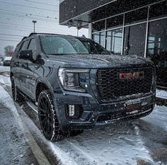 a black truck parked in front of a building covered in snow