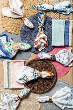 several different types of cloths and scarves laid out on a woven tablecloth