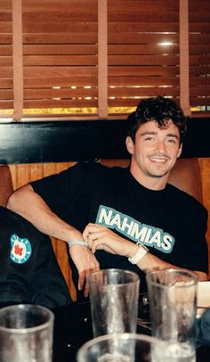 two men sitting next to each other at a table with cups and glasses on it