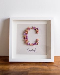 a white frame with a flower wreath in the shape of the letter c on it