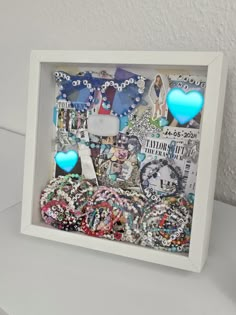 a white frame with blue heart shaped buttons in it and some other items on the table