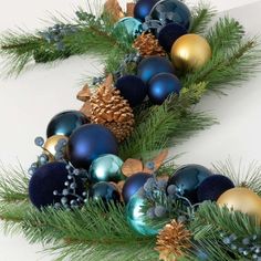 christmas garland with blue and gold baubles, pine cones and evergreen needles on white background