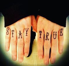 two hands with the words stay true tattooed on their palms, both holding each other