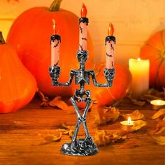 a skeleton candelabra with two candles in front of pumpkins and leaves