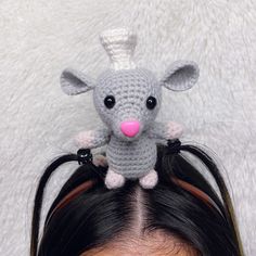 a crocheted mouse sitting on top of a woman's head with long black hair