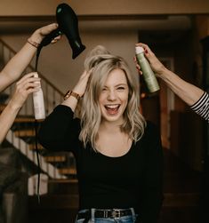 two women blow drying their hair while another woman holds her hair dryer over her head