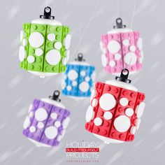 four lego style lights hanging from strings in the air with snow falling on them and white dots