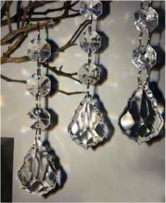 three crystal chandeliers hanging from a tree branch in front of a white wall