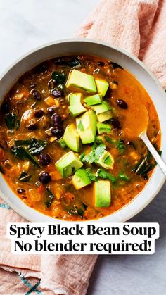 a bowl of black bean soup with avocado and spinach on the side