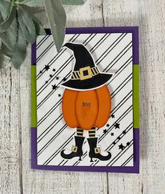 a halloween card with a cat wearing a witches hat and holding a pumpkin on it