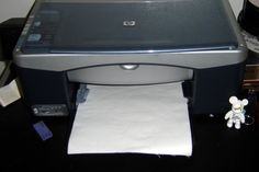 a printer sitting on top of a table next to a paper towel and a teddy bear