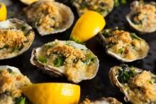 several oysters on a grill with lemons and parmesan crumbs