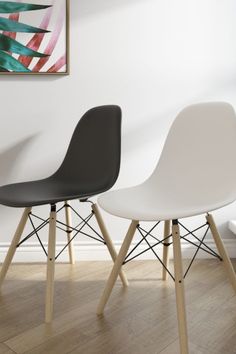 two black and white chairs sitting next to each other in front of a painting on the wall