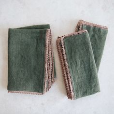 two green towels with crocheted edges on a white surface