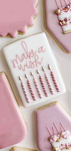 decorated cookies with pink icing and gold decorations on white table top, next to cookie cutters that spell out happy birthday