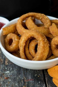 some onion rings in a white bowl on a wooden table