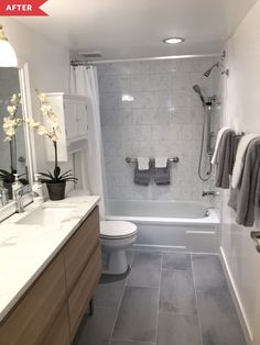 a white bathroom with gray tile flooring and walls