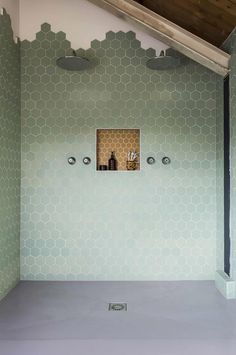 an empty bathroom with green hexagonal tiles on the walls