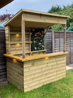 a small wooden bar with lights on the side and flowers on the wall behind it