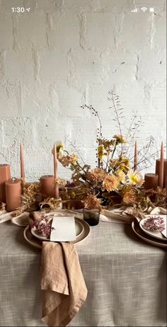 the table is set with candles, plates and napkins for an elegant fall dinner