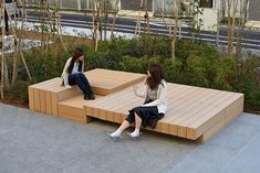 two women are sitting on wooden benches outside