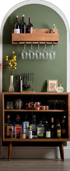 a bar with wine glasses and liquor bottles on the top shelf next to an arched doorway