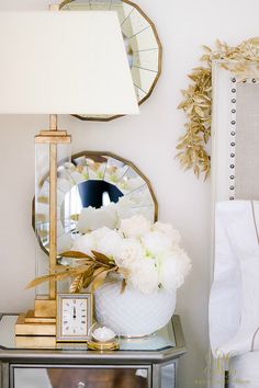 a white vase filled with flowers sitting on top of a table next to a mirror