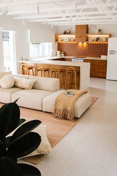 a living room filled with furniture next to a kitchen and dining area in the background