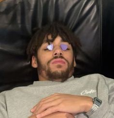 a man laying in a chair with his eyes closed and purple hearts on his forehead