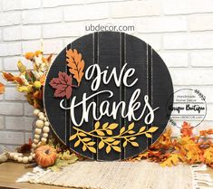 a wooden sign that says give thanks with fall leaves and acorns around it