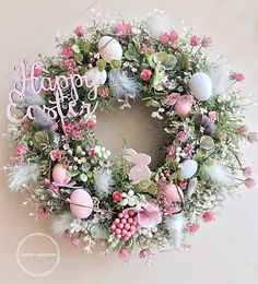 a happy easter wreath with pink and white eggs, flowers and greenery on it