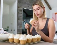 a woman sitting at a table with cupcakes in front of her and looking down