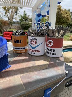 three buckets filled with silverware sitting on top of a table next to a pool