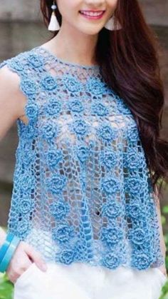 a woman with long brown hair wearing a blue crochet top and white skirt