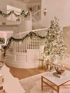 a christmas tree in the middle of a living room next to a spiral stair case