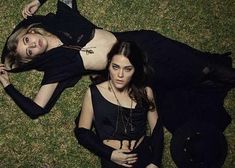 two women laying on the ground in black outfits