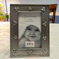 a silver frame sitting on top of a table with a baby's photo in it