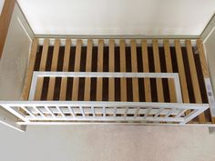 there is a wooden bed frame with white rails