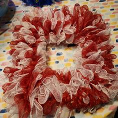 a red and white mesh wreath sitting on top of a polka dot tablecloth covered table