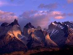 the mountains are covered in snow and have bright lights on them, as well as some clouds