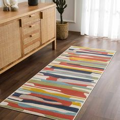 an area rug in the middle of a room with wooden flooring and white curtains